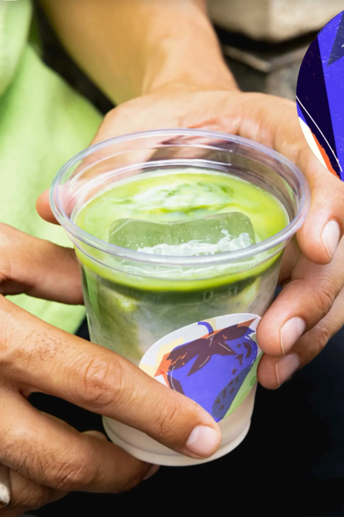 Hands sharing an iced matcha drink in a daytime social occasion