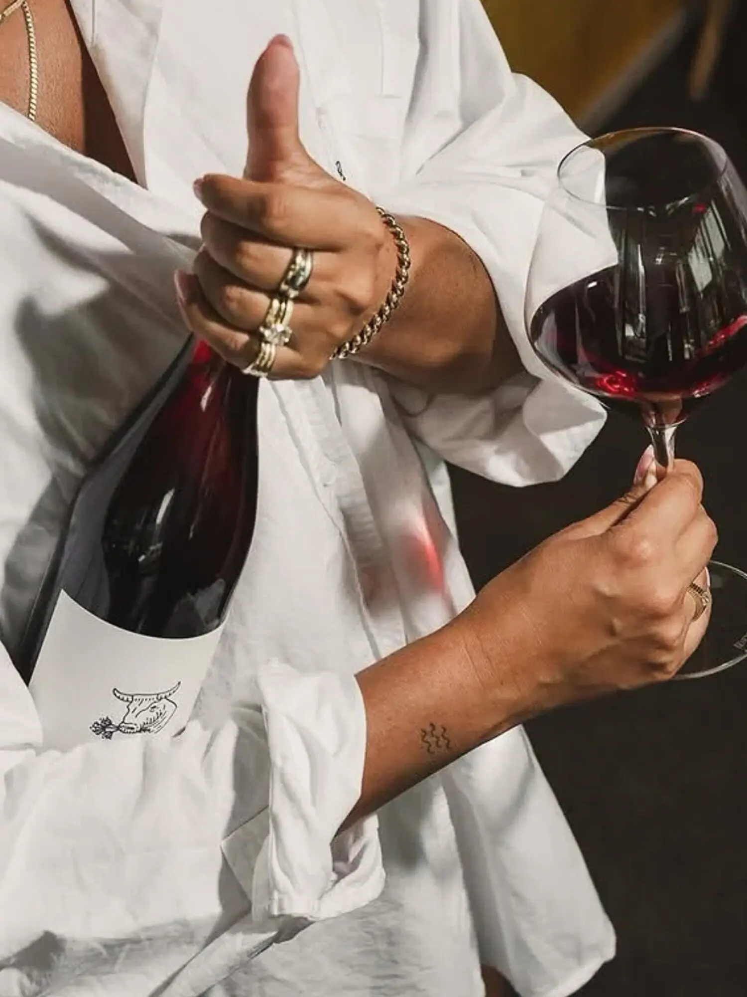 A person holding a wine bottle and glass in a casual service moment