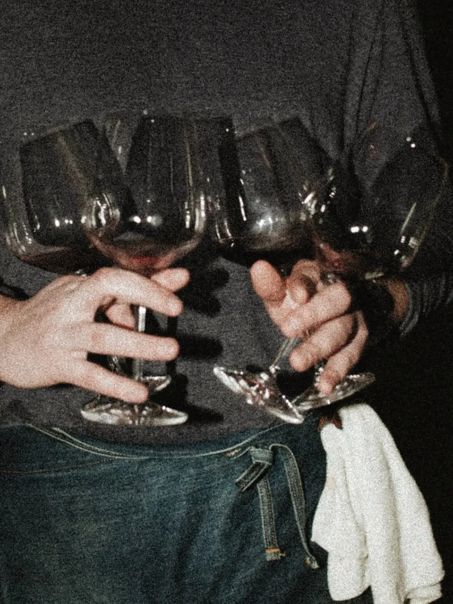 A group of friends holding red wine glasses during a dark social occasion