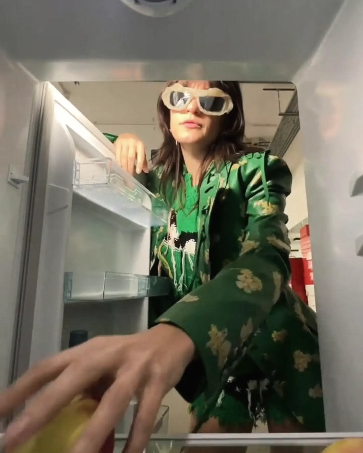 A shopper reaching into a refrigerator from the product point of view