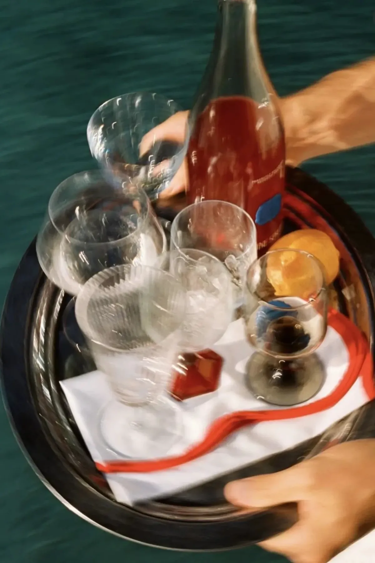 A hospitality tray carrying wine, glasses and fruit through a real service moment