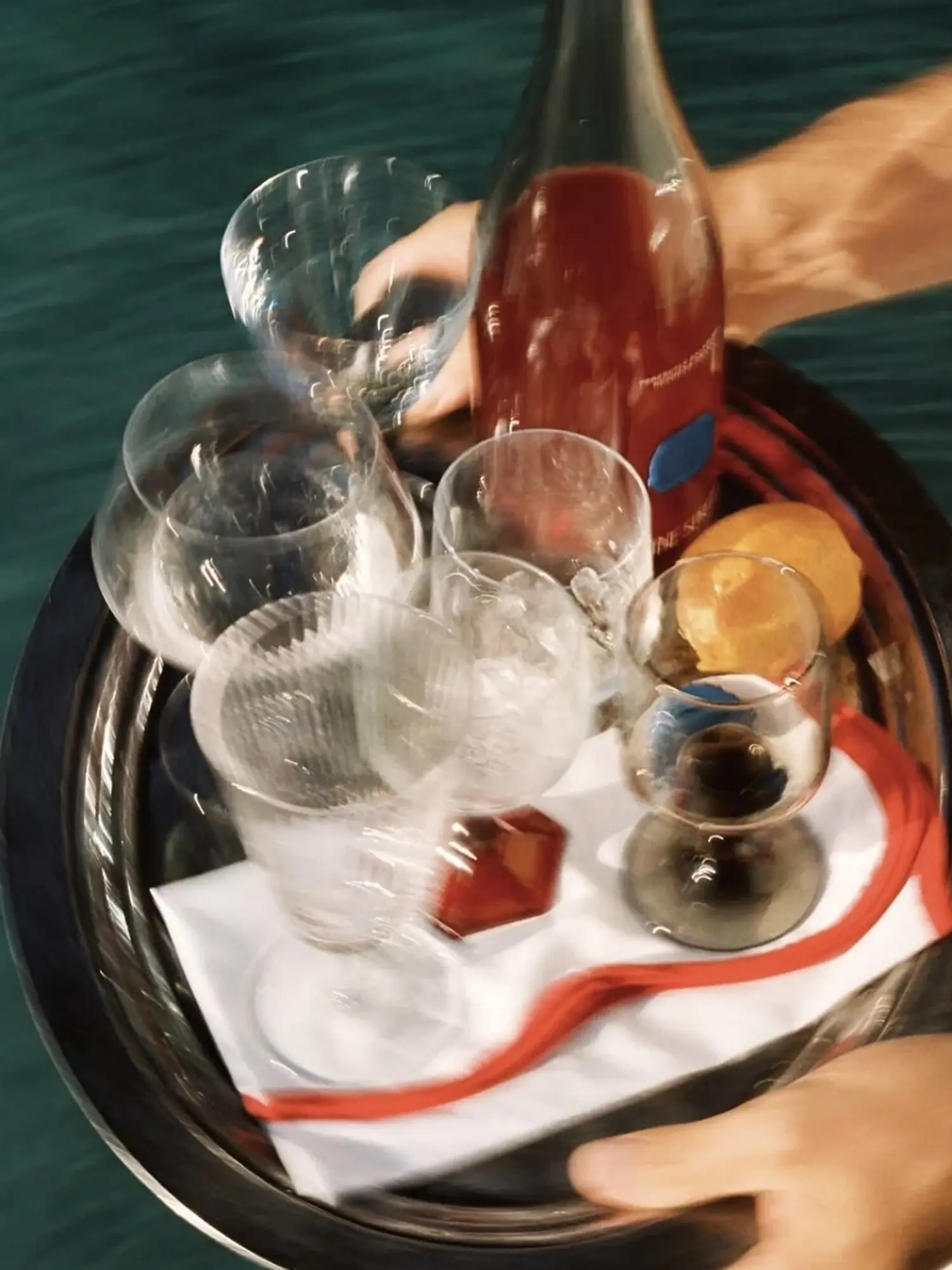 A hospitality tray carrying wine, glasses and fruit through a real service moment